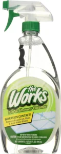 Clear spray bottle of The Works Tub and Shower Cleaner with green trigger removing rust and hard water stains.
